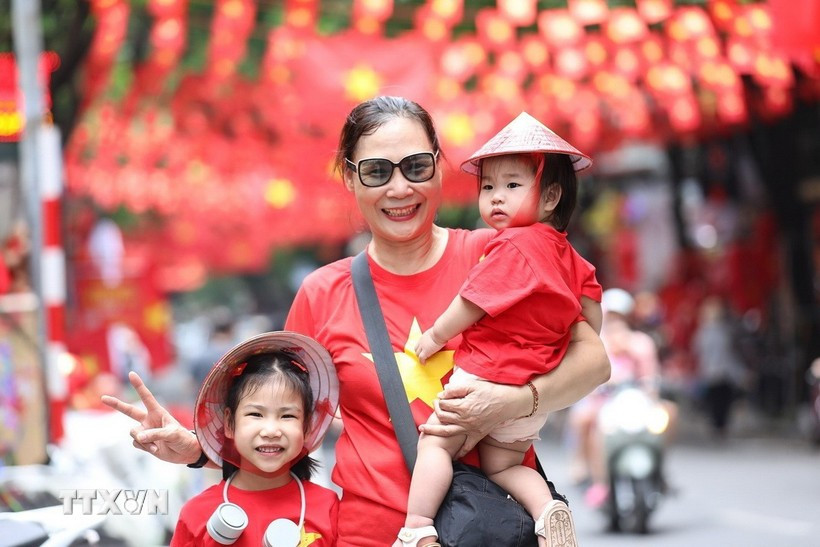 Numerosos habitantes capturan el momento con la imagen de la bandera nacional en la calle de Hang Ma, distrito de Hoan Kiem, Hanoi. (Foto: VNA)