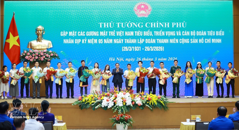 El primer ministro Pham Minh Chinh entrega flores para felicitar a los jóvenes vietnamitas destacados. (Fuente: VNA)