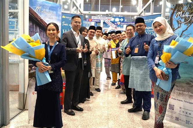 Representantes de Vietnam Airlines, Departamento General de Turismo de Malasia y el Aeropuerto Internacional de Kuala Lumpur esperan para recibir a los primeros pasajeros del vuelo Hanoi-Kuala Lumpur en la noche del 1 de abril de 2025. (Fuente: VNA)