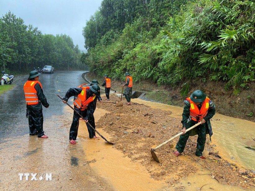 Guardias fronterizos de la ciudad de Hue excavan tierra y rocas para nivelar la carretera afectada por el deslizamiento de tierra en el Paso de Pe Ke, comuna de A Luoi 1. (Foto: VNA)