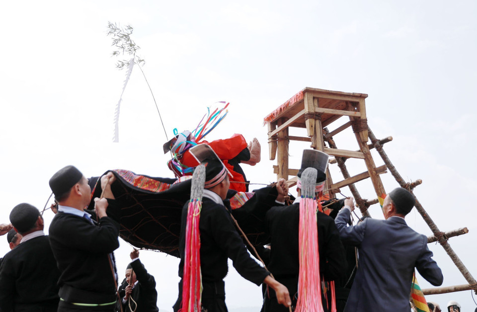 Bajo la guía del chamán, el joven se abraza las rodillas y se deja caer libremente, simbolizando su transformación en un adulto. (Foto: VNA)
