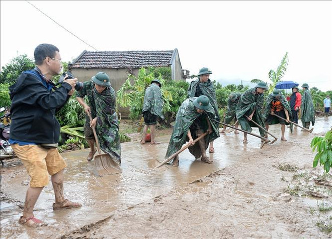 Un reportero de la VNA toma fotos de las actividades de superación de las secuelas de lluvias e innundaciones en la comuna de Tan Lap, distrito de Luc Ngan, provincia norteña de Bac Giang. (Foto: VNA) hình_ảnh (14).jpg