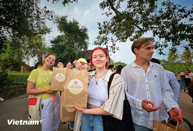 Los turistas extranjeros reciben recuerdos después de visitar la antigua aldea de Duong Lam en el distrito de Son Tay de Hanoi. (Foto: VietnamPlus) duong lam.jpg