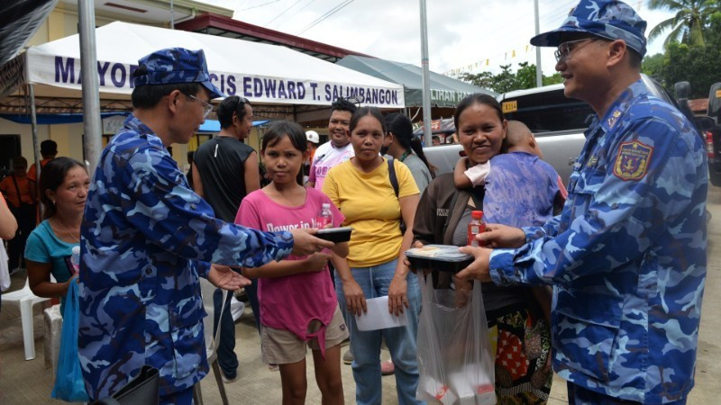 Un oficial de la delegación de la Guardia Costera de Vietnam presenta porciones de comida a los residentes afectados por el terremoto en la provincia de Bogo, Filipinas. (Foto: nhandan.vn)