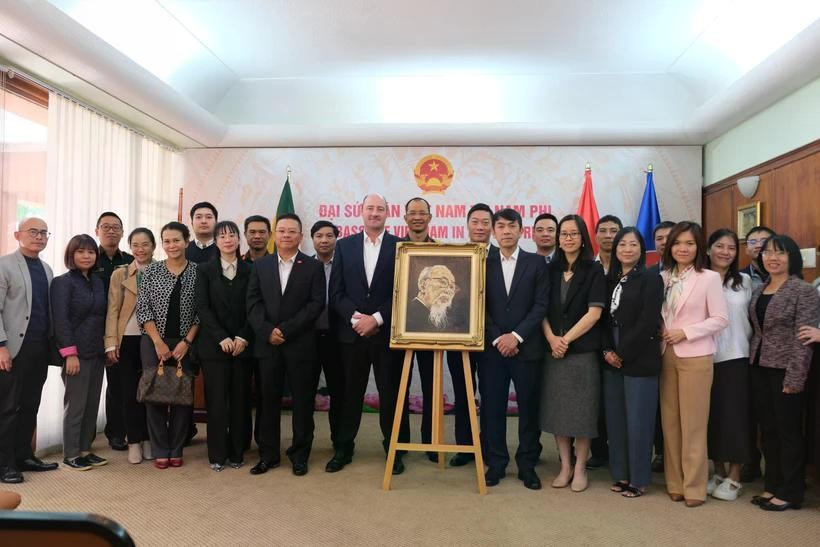 El embajador de Vietnam en Sudáfrica, Hoang Sy Cuong, y otros delegados posan para una foto conmemorativa con la familia del artista sudafricano Jan van Rooyen junto a su retrato al óleo del Presidente Ho Chi Minh. (Foto: VNA)
