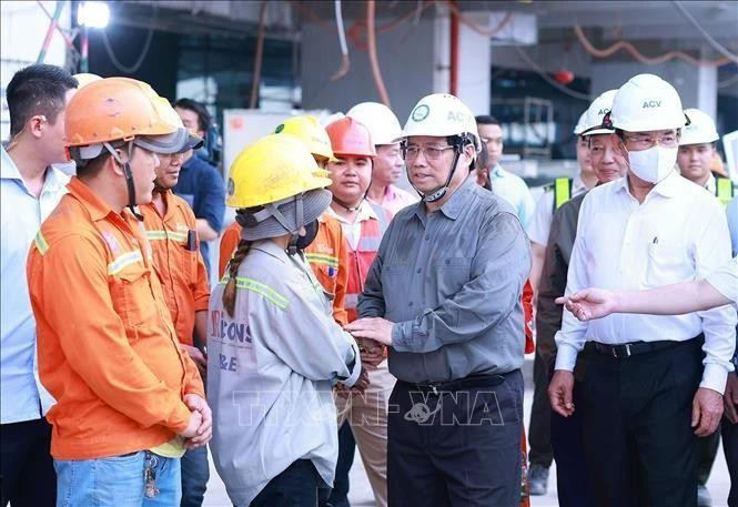 El primer ministro Pham Minh Chinh (segundo desde la derecha) felicita por el Año Nuevo a los trabajadores de la obra de construcción de la Terminal 3 del Aeropuerto Internacional de Tan Son Nhat en Ciudad Ho Chi Minh. (Foto: VNA)