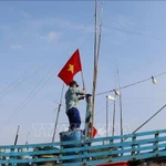 Pescadores izan la bandera de la Patria antes de zarpar para reafirmar la soberanía sobre las islas y mares de la Patria. (Foto: VNA)