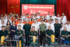 El secretario general del partido y presidente del Estado, To Lam (centro, de pie, primera fila), posa para una foto grupal con el personal, los inválidos y los soldados enfermos en el Centro de Atención para Inválidos de Thuan Thanh. (Foto: VNA)