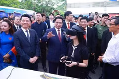 El primer ministro Pham Minh Chinh y otros delegados visitan las áreas de exhibición que presentan productos innovadores y de transformación digital de universidades y empresas. (Foto: VNA)