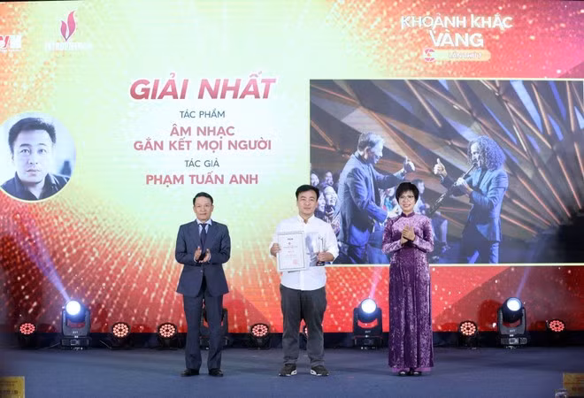 La directora general de la VNA, Vu Viet Trang (derecha), y el vicepresidente permanente de la Asociación de Periodistas de Vietnam, Nguyen Duc Loi (izquierda), entregan el primer premio a Pham Tuan Anh en el evento. (Foto: VNA)