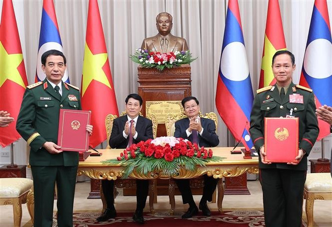 El presidente de Vietnam Luong Cuong (de pie, a la izquierda), y el secretario general del Partido Popular Revolucionario y presidente de Laos, Thongloun Sisoulith, presencian la firma e intercambio de una Carta de Intención entre los Ministerios de Defensa de Vietnam y Laos. (Foto: VNA) vna-potal-chu-tich-nuoc-va-tong-bi-thu-chu-tich-nuoc-lao-chung-kien-le-ky-van-kien-hop-tac-giua-hai-nuoc-7993380.jpg