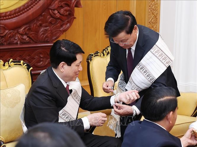 Thongloun Sisoulith ata un hilo a la muñeca del presidente Luong Cuong (Foto: VNA) vna-potal-chu-tich-nuoc-cung-tong-bi-thu-chu-tich-nuoc-lao-du-le-buoc-chi-theo-truyen-thong-lao-stand.jpg