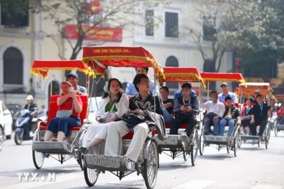 Turistas extranjeros experimentan un recorrido en triciclo alrededor del lago Hoan Kiem en Hanoi (Foto: VMA)