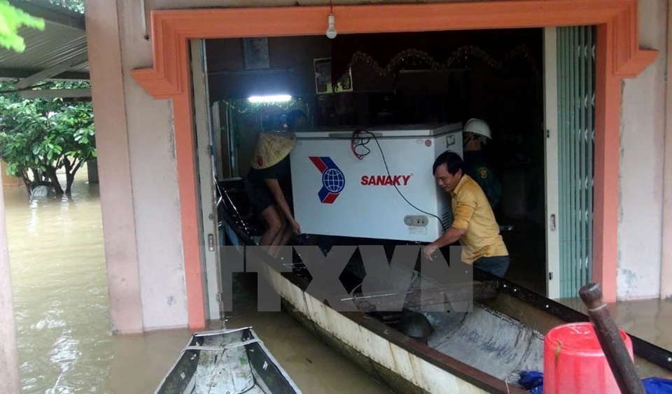 Las personas ayudan a una familia local a evacuar activos en un área inundada en la provincia de Quang Tri (Foto: VNA) 