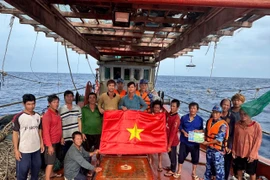 Las fuerzas de seguridad marítima de Ciudad Ho Chi Minh entregan la bandera nacional y difunden medidas preventivas contra la IUU a los pescadores (Foto: VNA)