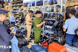 Las autoridades inspeccionan y confiscan una gran cantidad de productos de origen desconocido en una tienda (Foto: VNA)