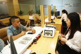 Clientes realizan transacciones en el banco Agribank (Foto: https://hanoimoi.vn/)
