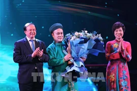 La directora general de la VNA, Vu Viet Trang (derecha), y el viceministro de Cultura, Deportes y Turismo, Ta Quang Dong (izquierda), entregan el premio de Artista inspirador a Chu Bao Que. (Foto: VNA)