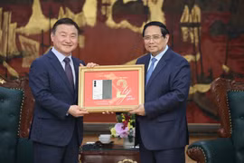 El primer ministro Pham Minh Chinh (derecha) entrega una placa conmemorativa de la producción del teléfono móvil número dos mil millones de Samsung en Vietnam a Roh Tae Moon (Foto: baochinhphu.vn)