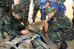 Los miembros del equipo AMET practican la recepción y sujeción de un paciente en una camilla para su traslado a una ambulancia (Foto: VNA)