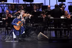 El artista Dang Ngoc Long y la Orquesta Sinfónica de Tubinga (Alemania) en el concierto "Una rapsodia de dos mundos" en el Teatro Ho Guom (Hanoi) en diciembre de 2025. (Foto: VNA)