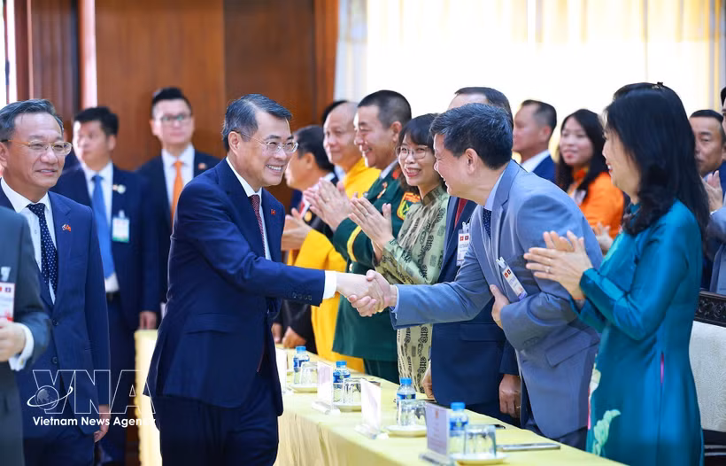 El primer ministro vietnamita, Le Minh Hung, y los funcionarios de la Embajada y representantes de la comunidad de connnacionales en Laos. Foto: VNA