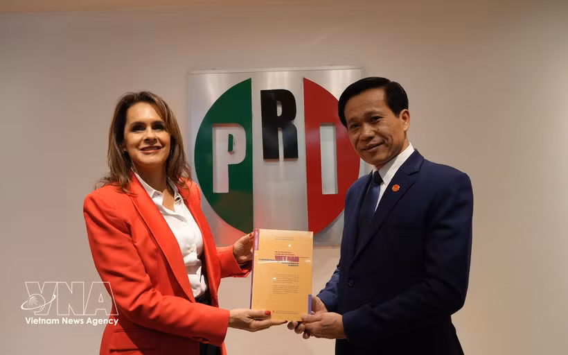 El subdirector de la Academia Nacional de Política Ho Chi Minh, Hoang Phuc Lam, entrega el libro "La aspiración de un Vietnam fuerte y próspero en la nueva era" a Sofia Carvajal, secretaria de Asuntos Internacionales del Partido Revolucionario Institucional (PRI). Foto: VNA