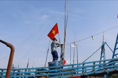 Pescadores izan la bandera de la Patria antes de zarpar para reafirmar la soberanía sobre las islas y mares de la Patria. (Foto: VNA)