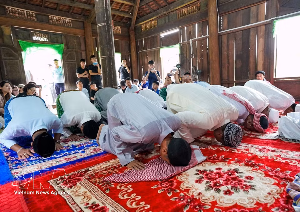 Hombres musulmanes Cham, vestidos con trajes tradicionales, acuden juntos a la mezquita para realizar las oraciones rituales. (Foto: VNA)