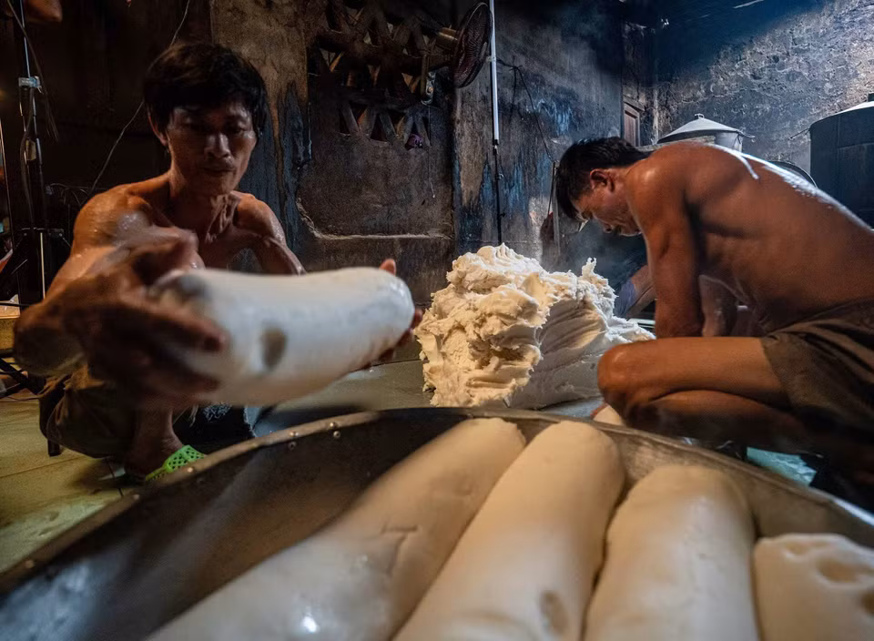 La harina de arroz, tras fermentar y cocer al vapor, se amasa hasta obtener una textura suave y luego se forma en grandes bloques cilíndricos. (Foto: VNA)