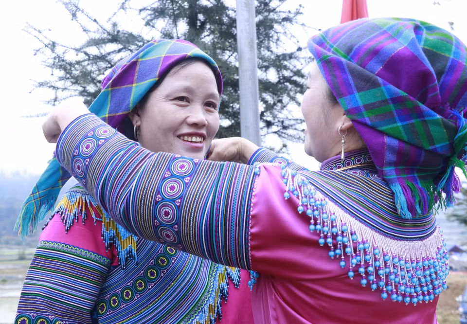 Las mujeres Mong se ayudan entre sí a ajustar sus atuendos tradicionales antes de unirse al festival. (Foto: VNA)