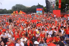 Numerosas personas con banderas rojas y estrellas amarillas en la intersección de Hung Vuong y Tran Phu esperan para presenciar el ensayo. (Fuente: VNA)
