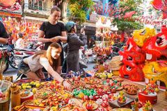 Las turistas extranjeras están interesadas ​​en conocer sobre los juguetes tradicionales vietnamitas del Festival del Medio Otoño. (Fuente: VNA)