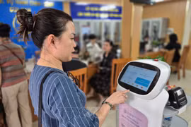 Ciudadana interactúa con un robot de IA que aplica tecnología de inteligencia artificial para ayudar en la realización de trámites administrativos en Hanoi. Foto: VNA