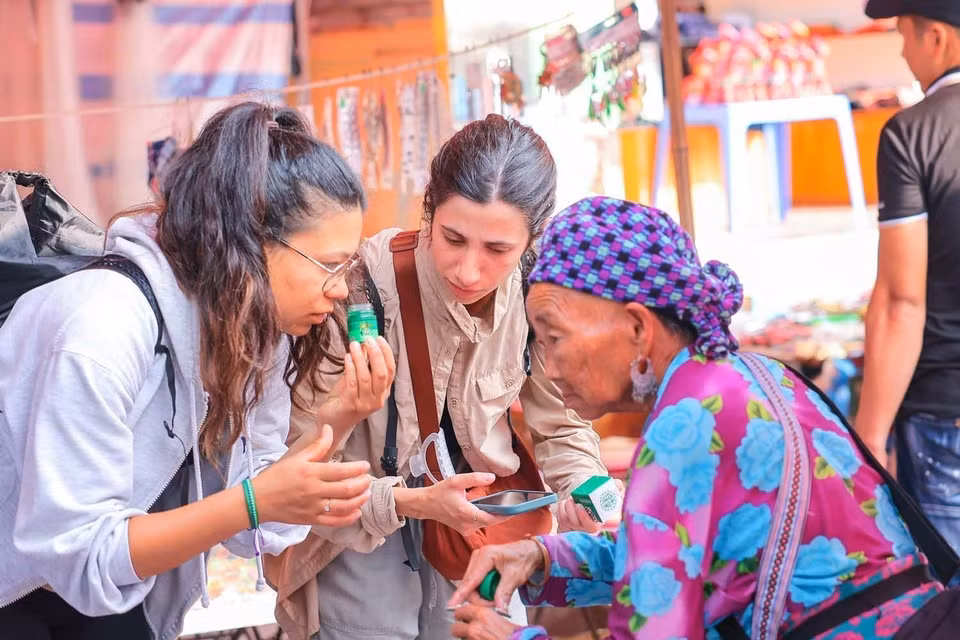 Turistas extranjeros exploran los productos disponibles en los mercados locales durante su visita a la meseta blanca de Bac Ha. Foto: VNA