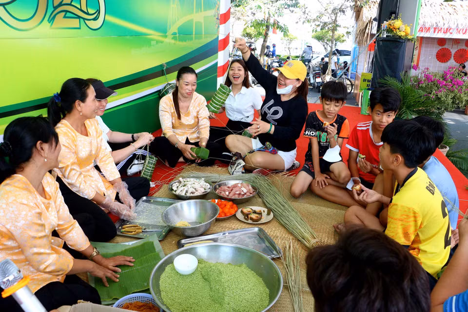 Turistas y pobladores locales comparten la experiencia de elaborar el “banh tet” o pastel cilíndrico de arroz glutinoso, una tradición culinaria del sur de Vietnam. (Foto: VNA)