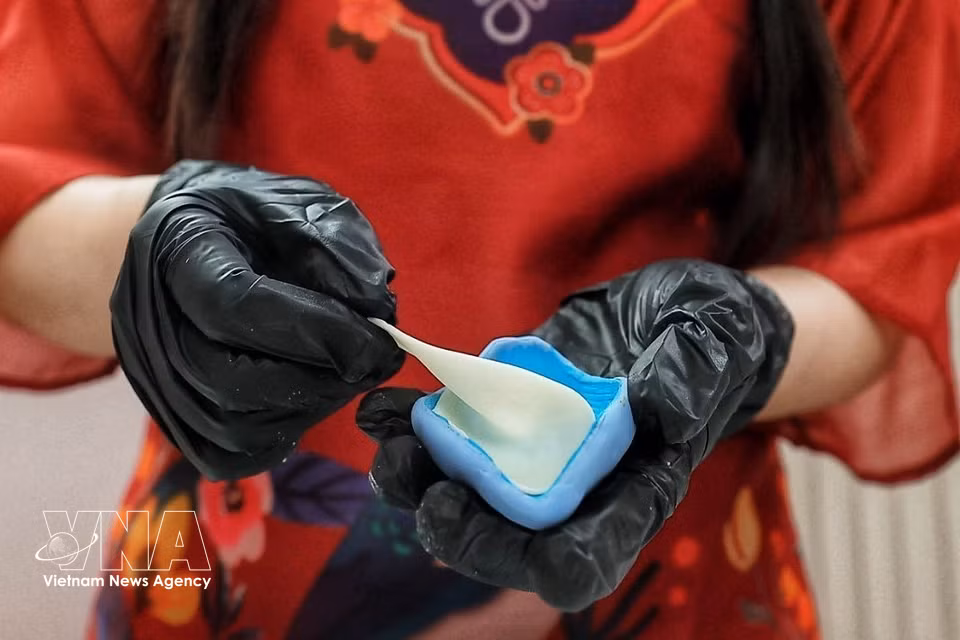 Cada pétalo se moldea con masa de tò he, se aplana y se le da forma manualmente antes de ensamblarlo para crear la flor. Esta técnica permite conseguir curvas, finura y contornos naturales. (Foto: VNA)