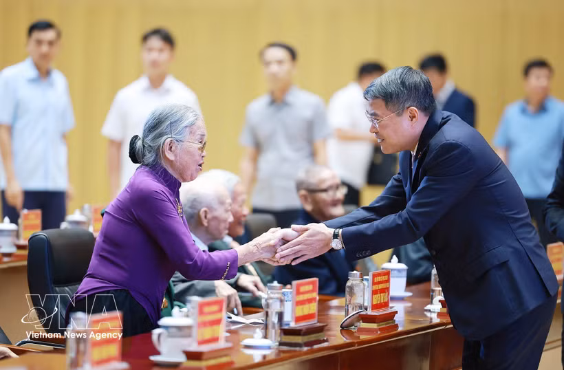 El primer ministro Le Minh Hung saluda a los militantes mayores. (Foto: VNA)