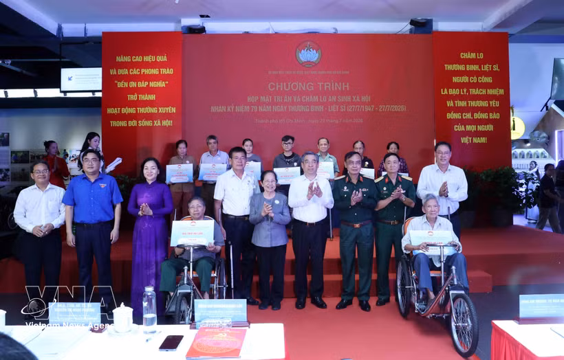El subsecretario del Comité del Partido de Ciudad Ho Chi Minh y presidente del Comité municipal del Frente de la Patria de Vietnam, Nguyen Phuoc Loc (cuarto desde la derecha), entrega obsequios a las familias beneficiarias de políticas sociales. (Foto: VNA)