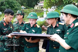 El coronel Ha Van Ai, subcomisario político del Mando Militar de la ciudad de Hue (tercero por la izquierda), señala en un mapa el lugar de enterramiento de un soldado caído. Foto: VNA
