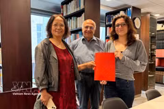 La investigadora cultural Tran Thu Dung (izquierda), Yonnel Ghernaouti, miembro de la Junta Directiva del Instituto Masónico de Francia, y Emma Lallemand, bibliotecaria del GODF, posan para una fotografía con documentos de archivo sobre Nguyen Ai Quoc. Foto: VNA