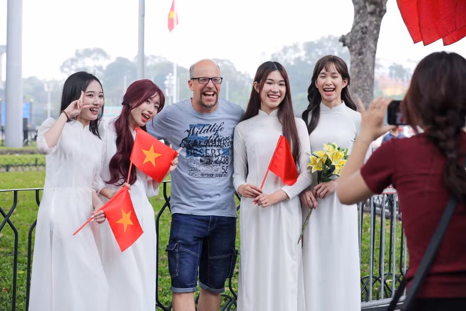 Visitantes extranjeros disfrutan tomándose fotos con la bandera vietnamita. (Fuente: VNA)