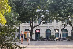 Turistas extranjeros pasean bajo los árboles frondosos a orillas del lago Hoan Kiem, disfrutando del ambiente fresco de la capital. (Foto: VNA)