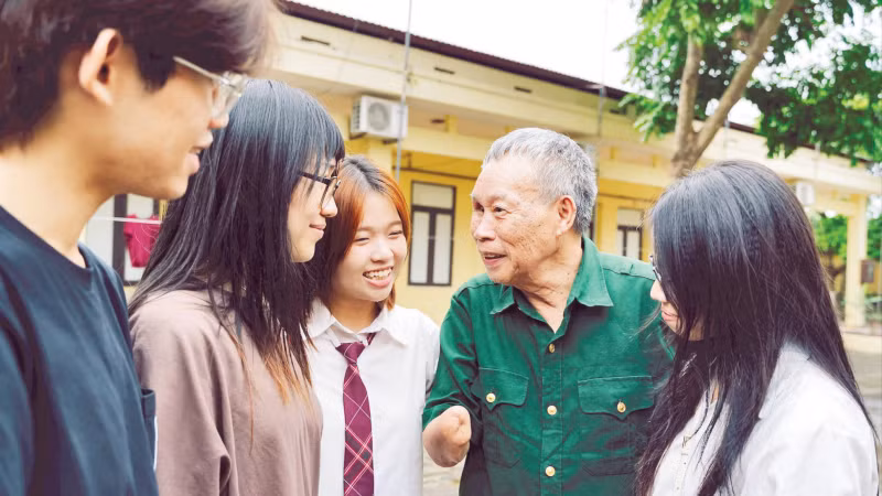 Los miembros del proyecto "Historias en tiempos de paz" escuchan el testimonio del veterano de guerra Do Dang Khuay. (Fuente: nhandan.vn)