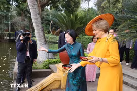Nguyen Thi Minh Nguyet, esposa del presidente Luong Cuong, y la reina Matilde de Bélgica, alimentan a los peces en el estanque de Tío Ho, en el sitio de reliquias del Presidente Ho Chi Minh. (Foto: VNA)