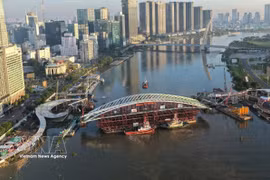 Vista panorámica de la barcaza que transporta el vano principal del puente peatonal sobre el río Saigón, situada en posición para su unión con la estructura. (Foto: VNA)