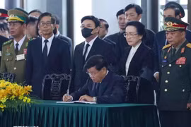 El secretario general del Partido Popular Revolucionario y presidente de Laos, Thongloun Sisoulith, escribe en el libro de condolencias. (Fuente: VNA)