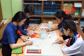 Alumnos de a escuela bilingüe laosiano-vietnamita de Nguyen Du pintan un cuadro del Tío Ho. (Fuente: VNA)