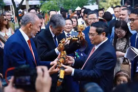 El primer ministro Pham Minh Chinh obsequia marionetas de agua a los delegados. (Foto: VNA)