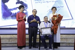 La directora general de VNA, Vu Viet Trang (primera, a la izquierda), entrega el Premio "Caballero Grillo" al compositor Pham Tuyen (sentado) durante la ceremonia. (Foto: VNA)